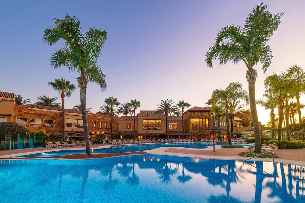 Piscina del resort rodeada de palmeras en Elba Costa Ballena