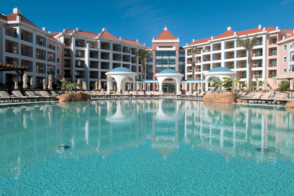 Hotel with a large pool in front at the resort