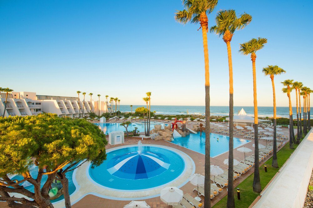 Resort pool area with loungers and surrounding gardens