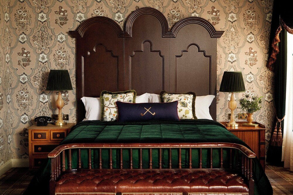 Dormitorio tradicional con un alto cabecero de madera y colcha verde