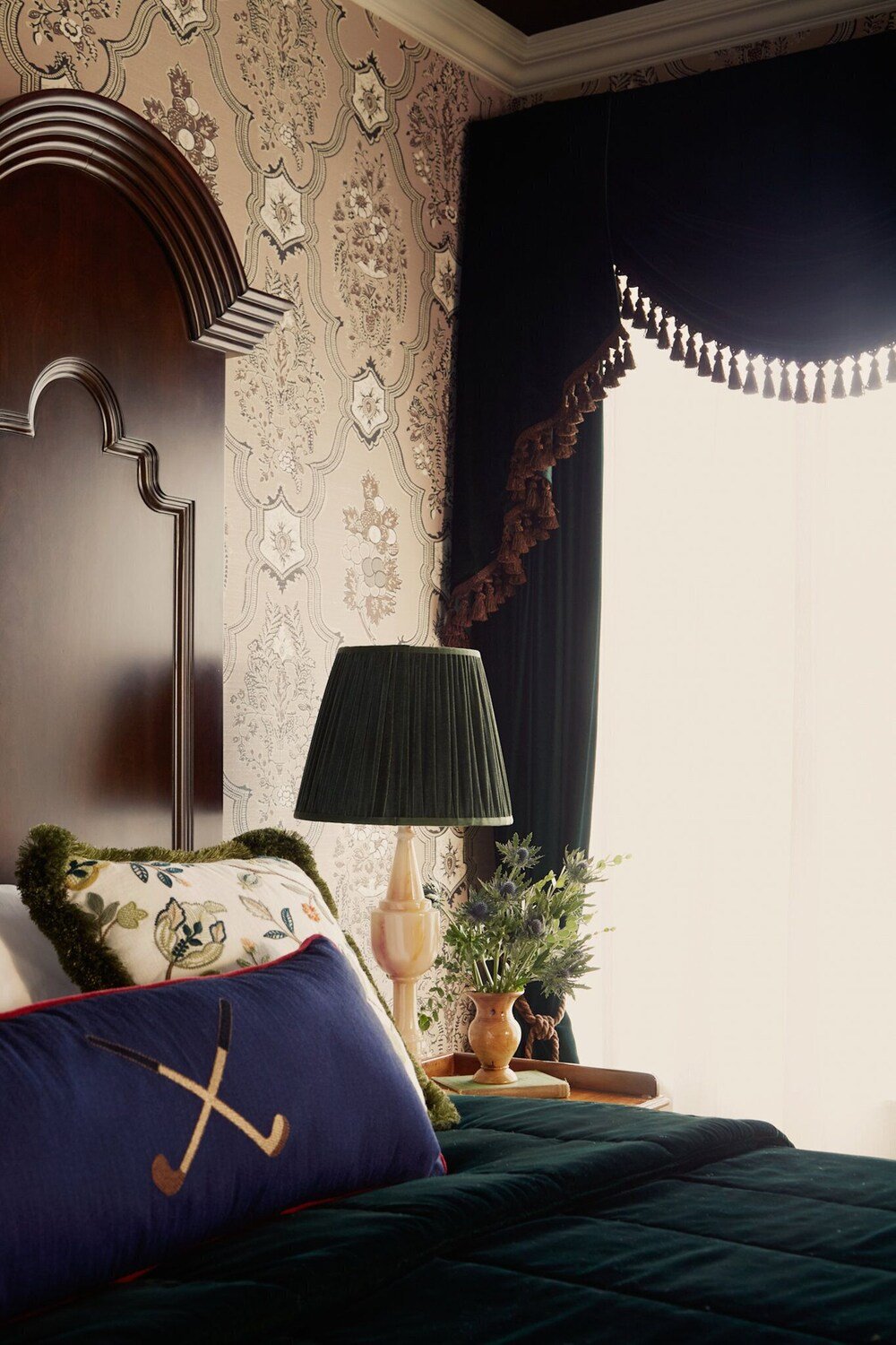 Dormitorio con cama, mesa de noche, lámpara y ventana con cortinas