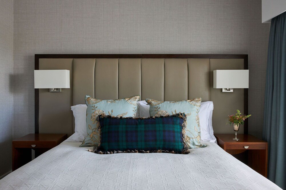 Neatly made bed with patterned pillow and two bedside lamps