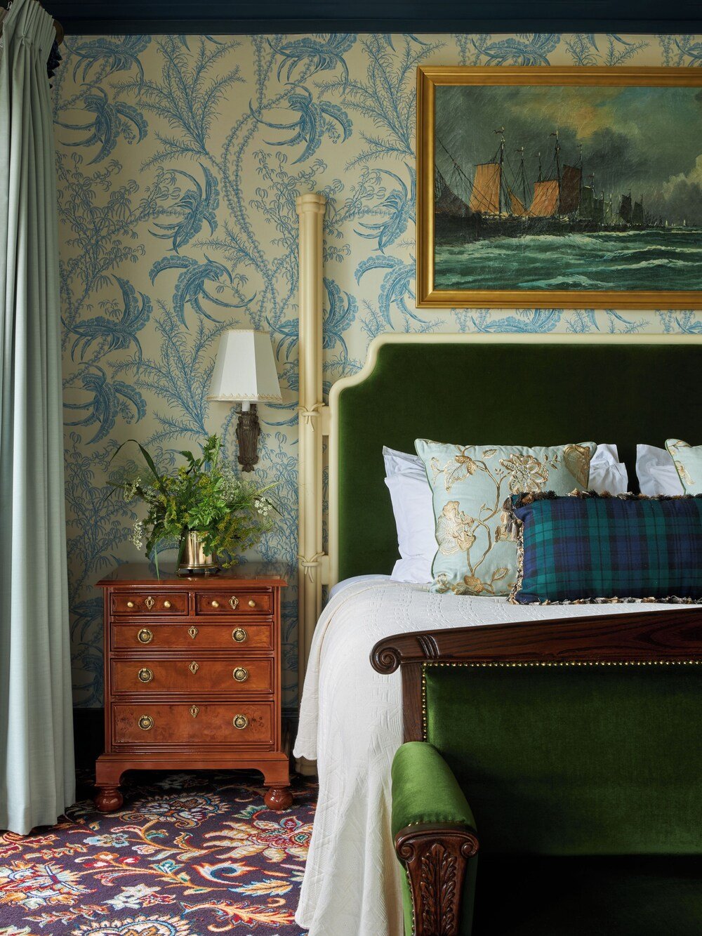 Bedroom with a green upholstered bed and wooden nightstand