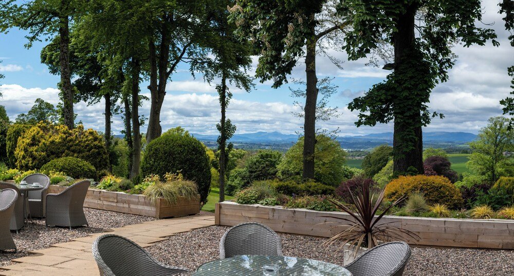 Outdoor patio with wicker furniture overlooking a landscaped garden