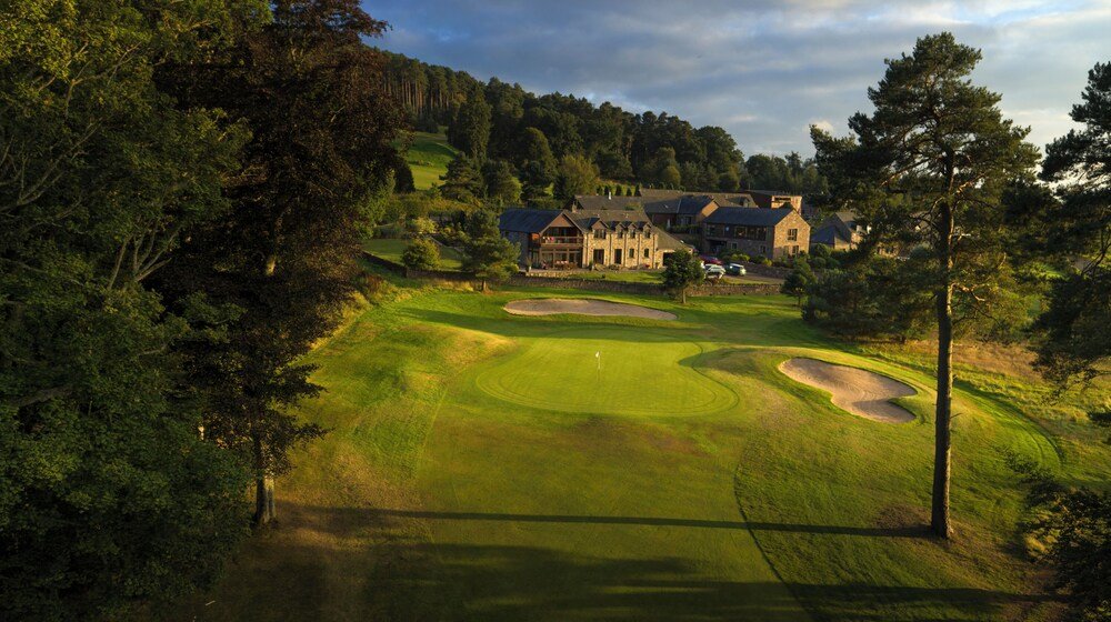 Golf course with a clubhouse and a large house behind