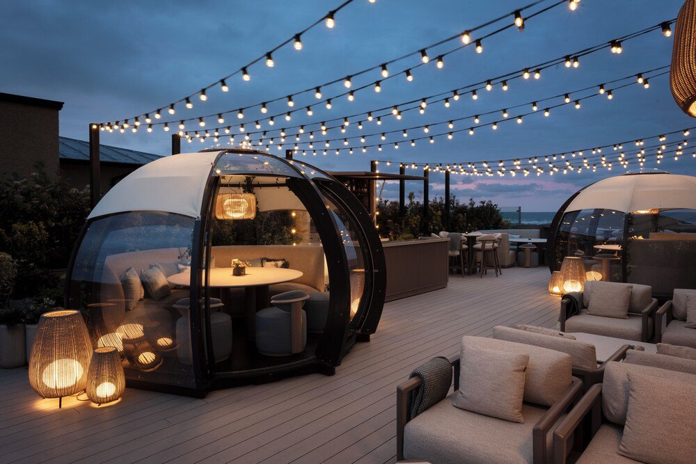 Rooftop terrace with string lights, seating and a glass-enclosed dining area
