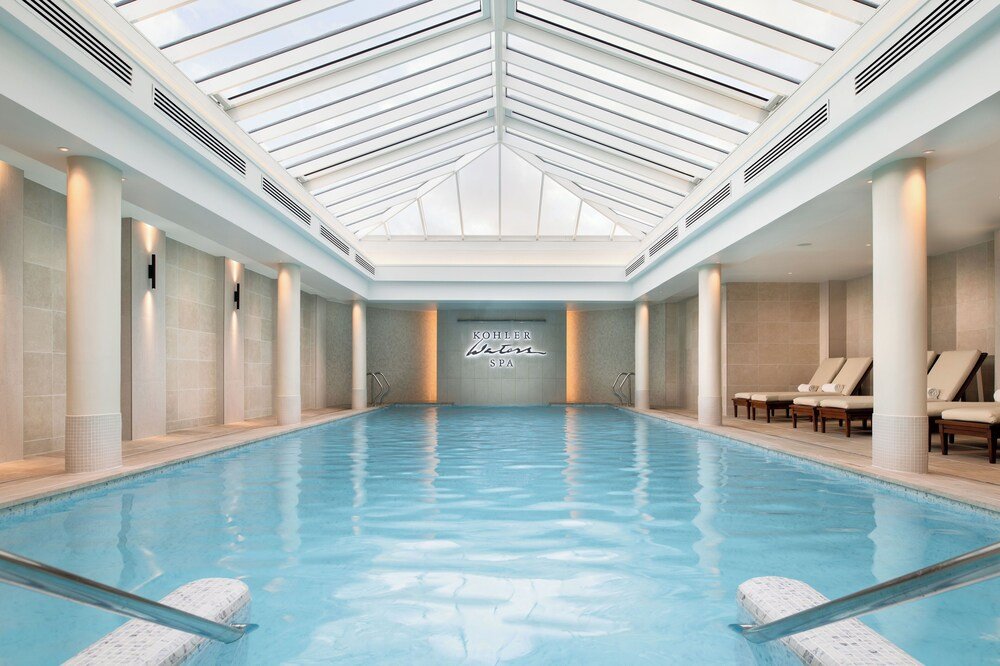 Gran piscina cubierta con claraboyas, columnas y reposeras