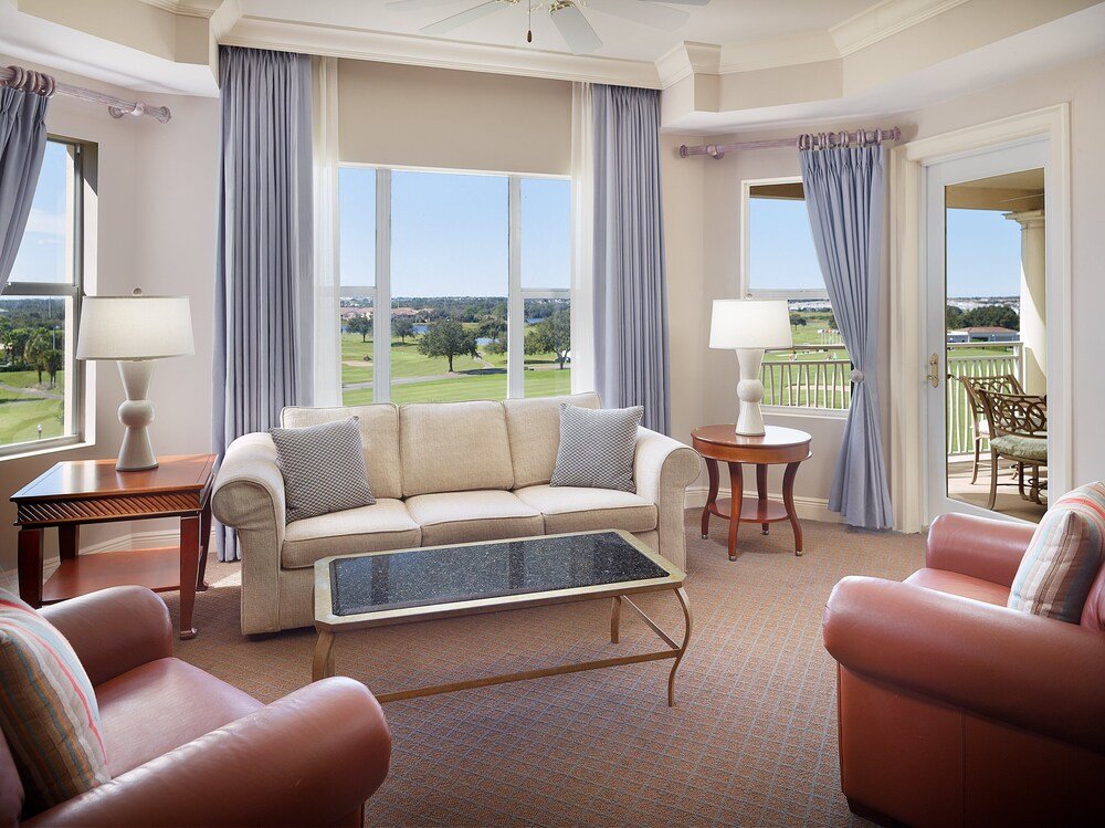 Well-lit living room area with a beige sofa in a suite