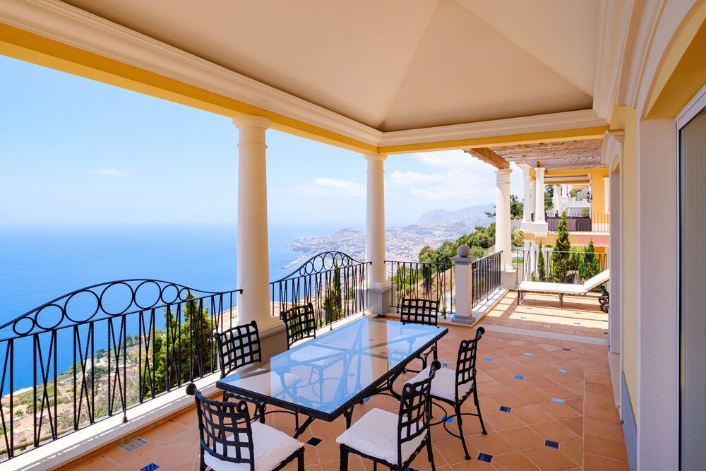 Balcony with a glass table and seating at Palheiro Village in Funchal, Madeira