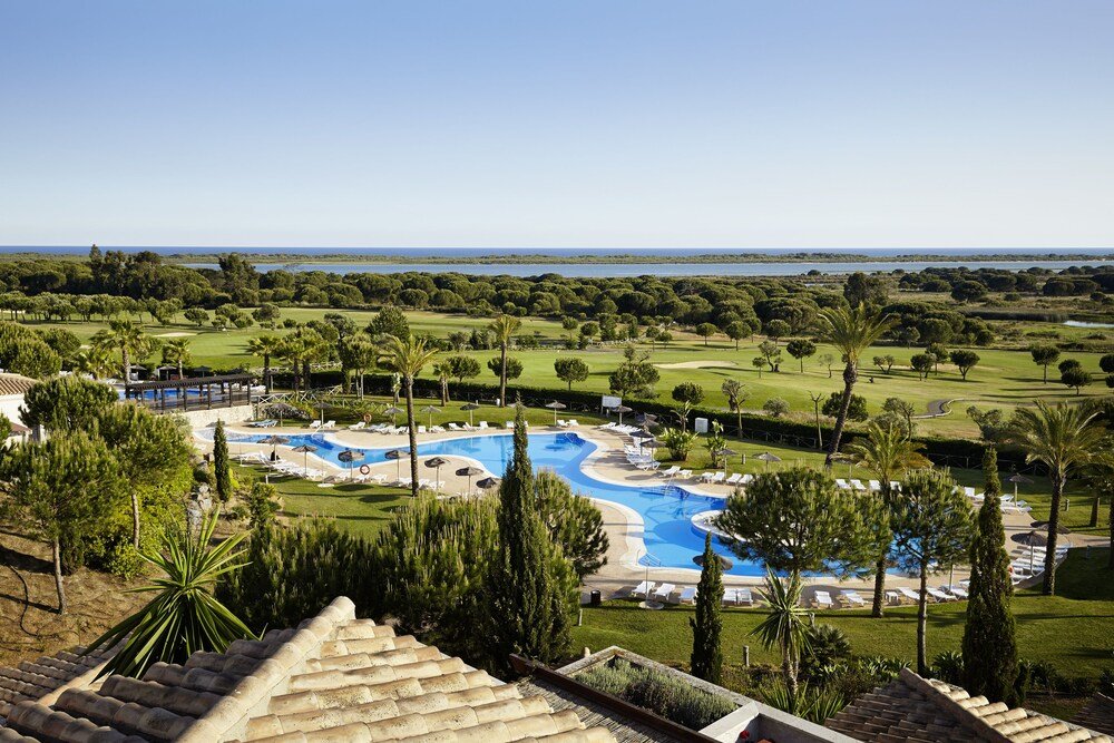 Resort swimming pool surrounded by buildings and terraces at El Rompido
