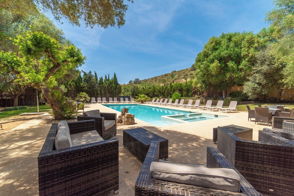 Pool area with wicker furniture at Pula Golf Resort in Son Servera, Mallorca