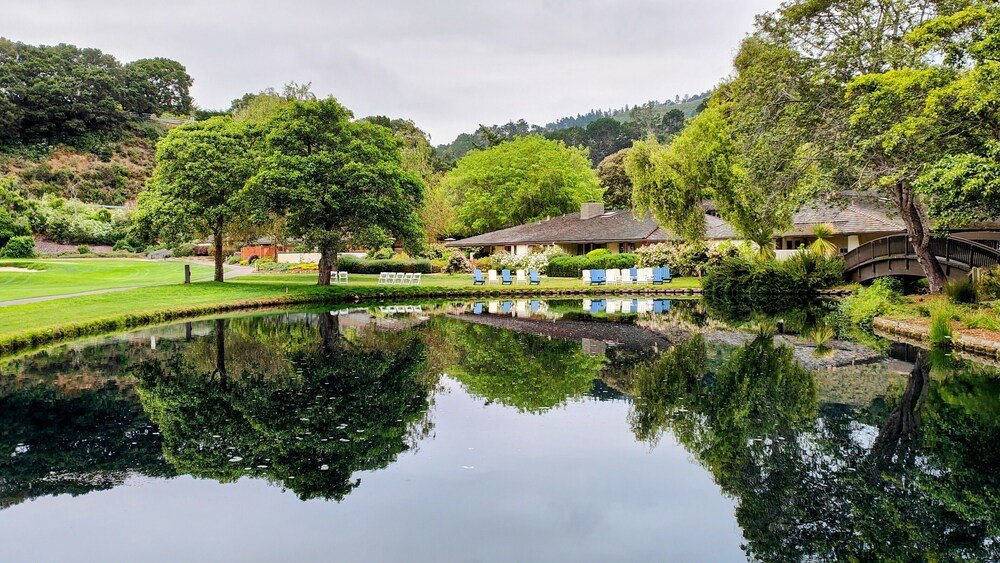 Calm pond reflecting trees and a resort building