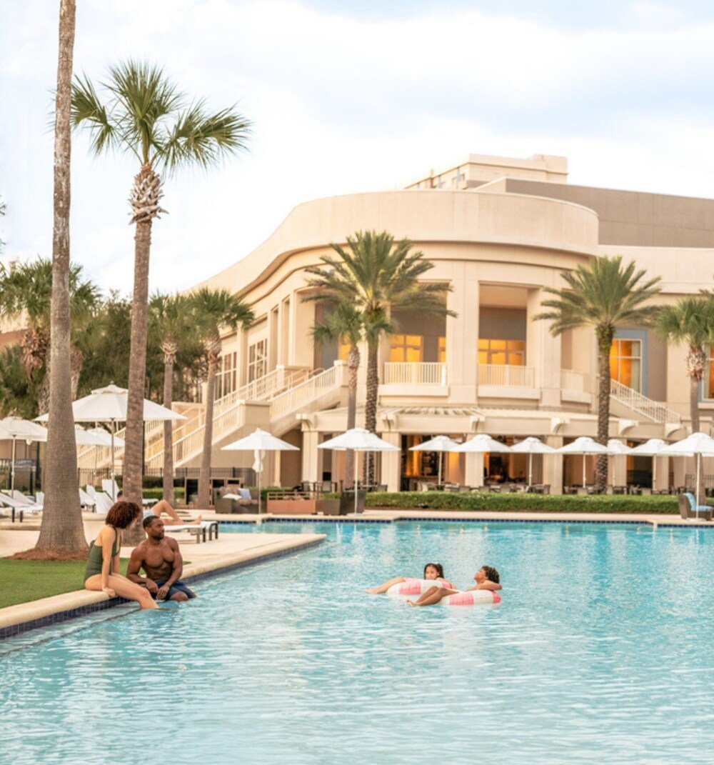 Swimming pool with palm trees and umbrellas at Waldorf Astoria Orlando